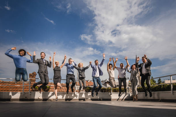 istock Happy business team jumping with raised arms on a terrace. 1192810954