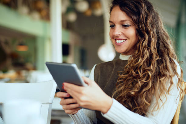 istock Attractive young curly brunette looking at her tablet and smiling 1192812112