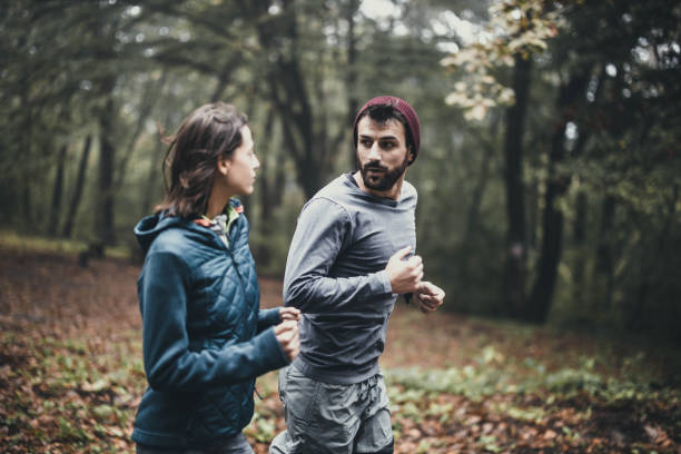 istock Athletic couple talking while running in misty forest. 1192812944