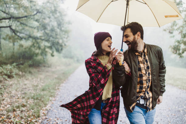 istock Cheerful couple communicating while taking a walk on a rainy day at forest. 1192813620