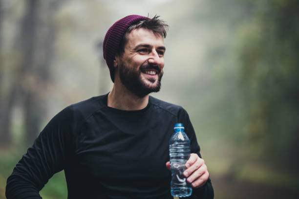 istock Happy male athlete resting on water break in nature. 1192814092
