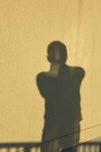 Shadow of a person on the rooftop with fence.