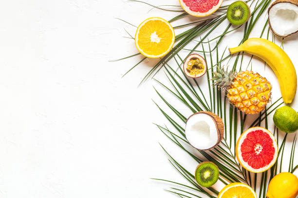 istock Tropical fruits and palm leaves on a white background 1192816355