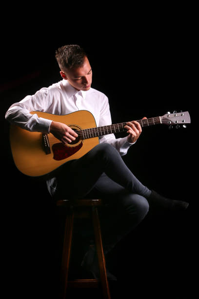istock Young men playing the guitar with black background 1192820693