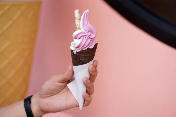 istock Hand holding two tone soft serve ice cream cone with natural yogurt and raspberry flavors on blurred background. 1192820945