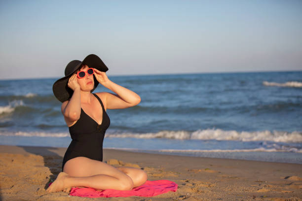 Elderly woman in a hat sunbathes