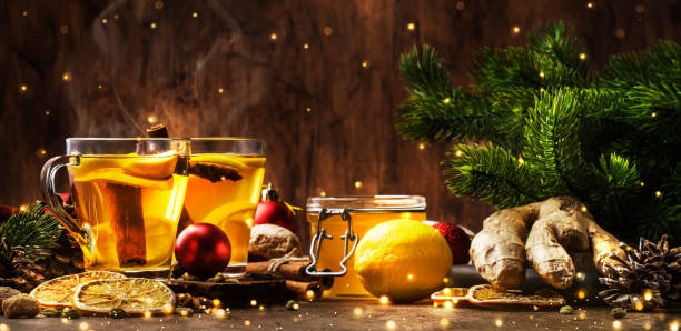 zimowa gorąca herbata z owocami, cytryną i przyprawami w szklanym kubku z parą w świątecznym lub noworocznym stole, rustykalne drewniane tło - ginger tea cup cold and flu tea zdjęcia i obrazy z banku zdjęć