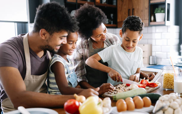 Happy family in the kitchen having fun and cooking together. Healthy food at home. Healthy food at home. Happy black family in the kitchen having fun and cooking together family dinners and cooking stock pictures, royalty-free photos & images