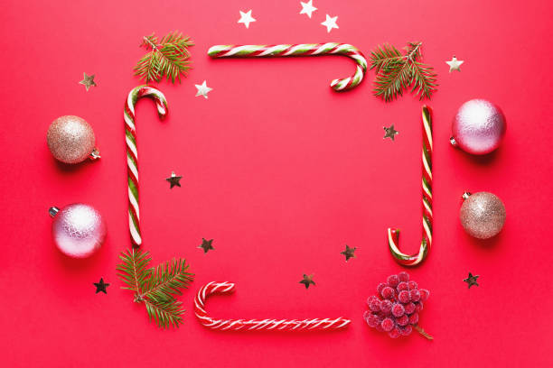 christmas baubles, golden decorations, candy canes frame, confetti on red background with copy space. christmas card with ornaments, top view - hard candy candy pink wrapping paper imagens e fotografias de stock