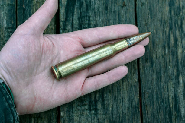 istock bullet in mans hand on wooden background 1192836531