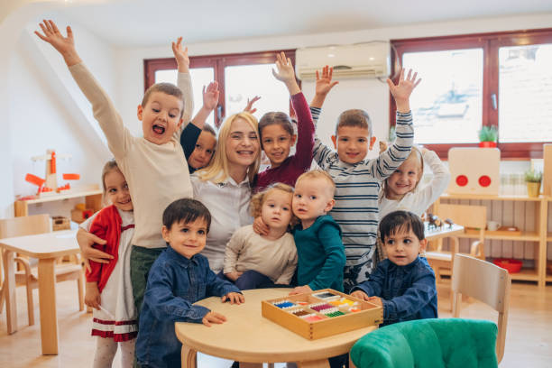 Group of children and woman, having fun together in preschool classroom.