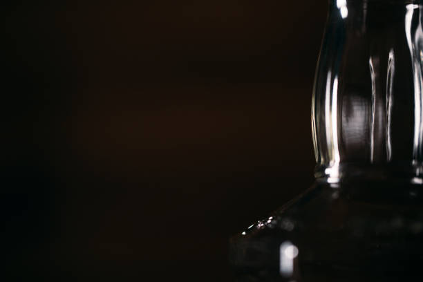 Macrophotos of a whiskey bottle in dim light on a wooden background. Macrophotos of a whiskey bottle in dim light on a wooden background. silver platter stock pictures, royalty-free photos & images