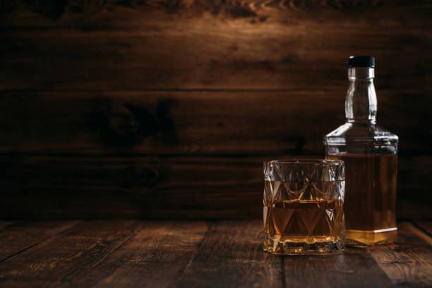 bouteille élégante de whisky avec un plein verre sur un fond en bois dans le modèle rétro - cigar whisky bar cognac photos et images de collection