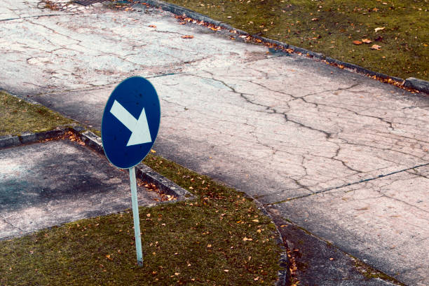 istock Arrow sign to an empty road in bad condition. 1192838015