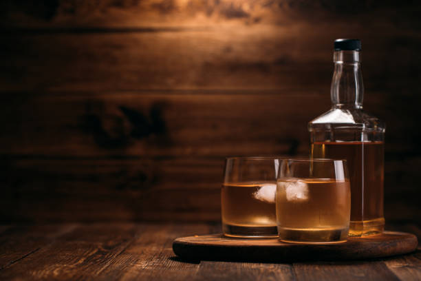 elegant whiskey bottle with a full glass on a wooden background in retro style - cigar whisky bar cognac imagens e fotografias de stock