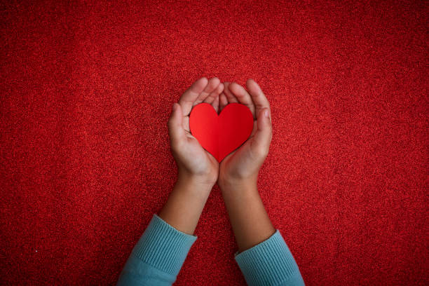 istock The heart symbol in the hand on red background 1192840407