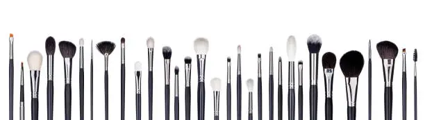Photo of Set of make-up brushes lined up in alternating pattern. Isolated on white