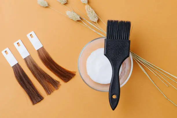 Photo of Composition of hair samples, bowl of die developer, black brush, cereal spikes