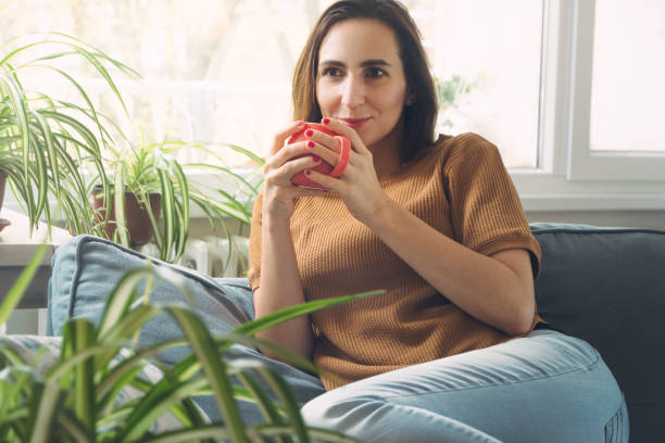 istock Woman sitting comfortable on sofa with tea. 1192842160