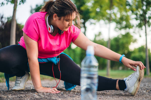 istock Young overweight woman stretching outdoor 1192844975