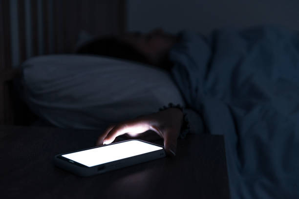 istock Woman reaching and switching off disturbing calls from work on smartphone while sleeping at midnight 1192846026