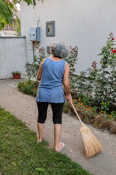 istock Senior Woman is Sweeping the Backyard with Broom 1192846115