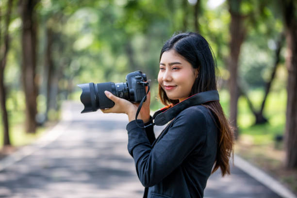istock Smiling Young Woman Looking Away While Photographing With Camera 1192848371