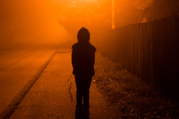 criança que anda através da estrada durante uma noite nevoenta. - spooky horror nostalgia autumn - fotografias e filmes do acervo