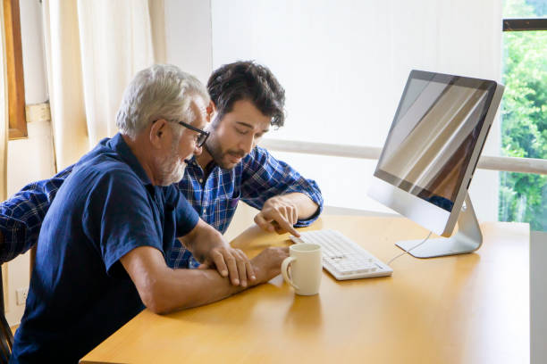 istock Man Showing Computer Key To Father While Sitting On Table At Home 1192852627