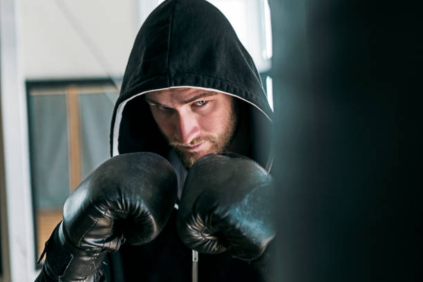 istock Young boxer during training with punching bag with hood 1192861447