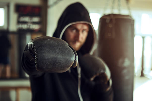 istock Young boxer during training with punching bag looking at camera 1192861466