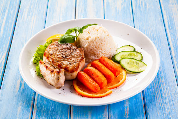istock Fried pork chop with rice and vegetables on wooden background 1192861659