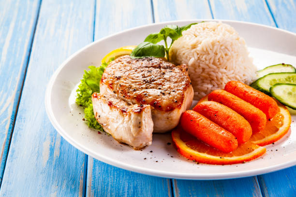 istock Fried pork chop with rice and vegetables on wooden background 1192862201