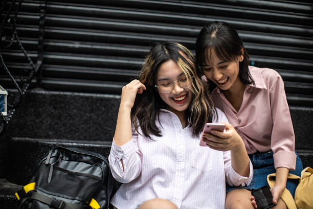 istock Asian friends using phone and laughing while sitting on steps before school 1192862345