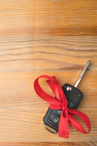 istock Car key with red bow on natural wooden table background. 1192863791