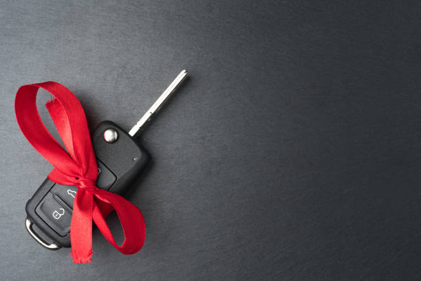 istock Car key with red bow on dark black slate plate. 1192863857