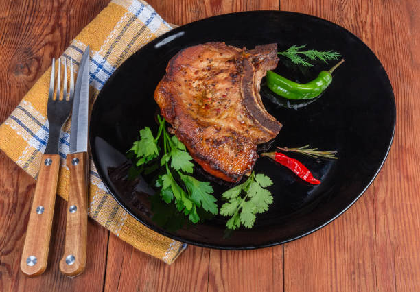 istock Grilled pork loin chop bone-in on dish, fork, knife 1192865083