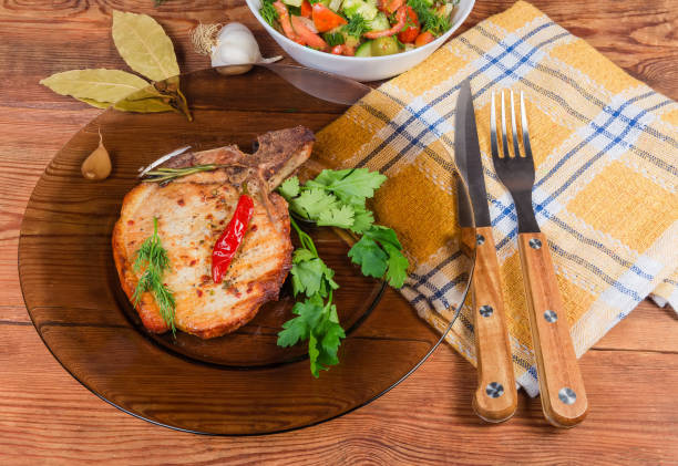istock Grilled pork loin chop bone-in on dish, fork, knife 1192865154