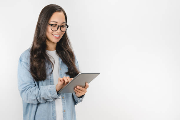 mujer joven sonriente usando una tableta aislada sobre fondo blanco - book young adult women student fotografías e imágenes de stock