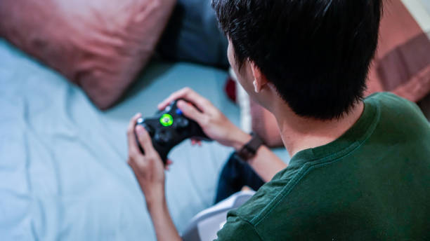 millennials asiatici emotivi che giocano a videogiochi a letto - overemotional foto e immagini stock