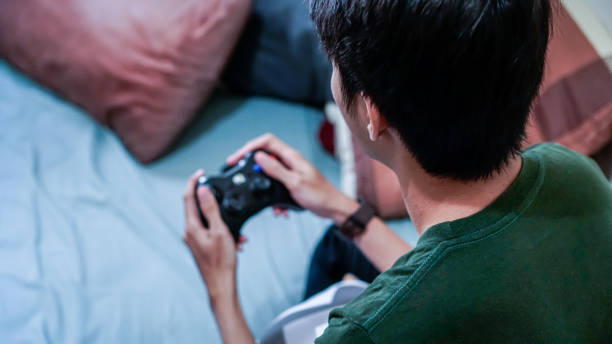 overemotional asian millennials playing video game in bed - overemotional imagens e fotografias de stock