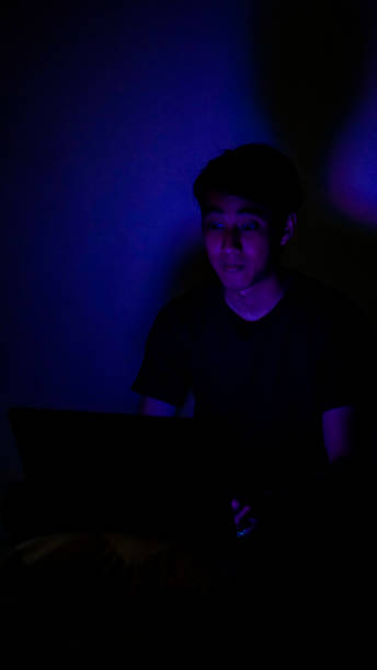 istock Asian Millennials Playing Game In The Dark Room Blue Background 1192867877