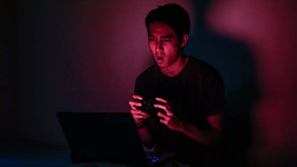 millennials asiatici emotivi che giocano al videogioco in sfondo rosso dark room - overemotional foto e immagini stock