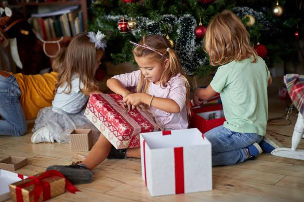 istock Kids opening Xmas presents. Children under Christmas tree with gift boxes. 1192873607