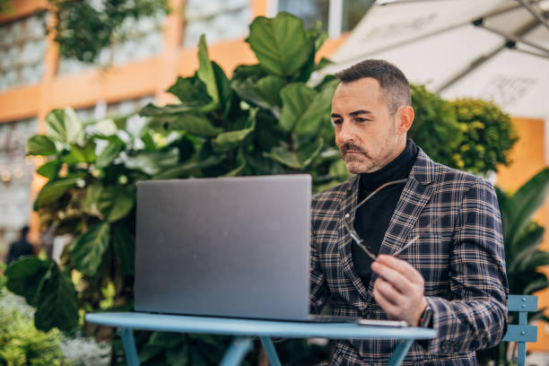 istock Businessman using laptop in sidewalk cafe 1192876455