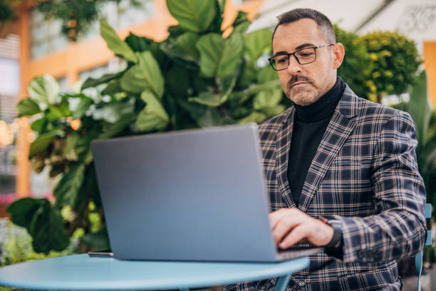 istock Modern gentleman using laptop in sidewalk cafe 1192877007