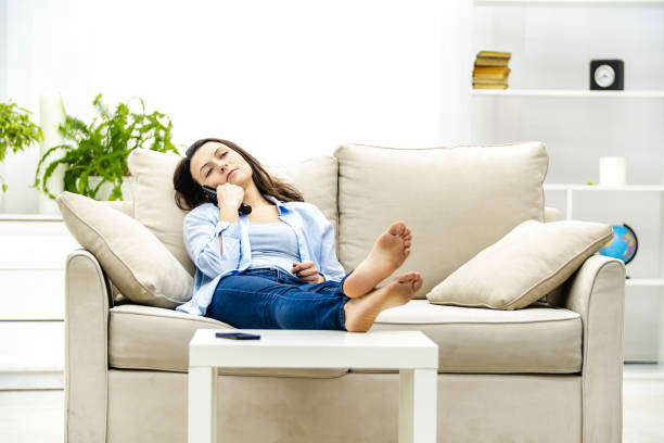 istock Bored young woman is watching TV, laying on a sofa. Copy space. 1192877947
