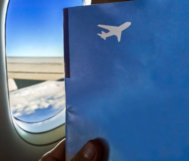 istock Sitting by window on a plane with magazine in hand 1192879542