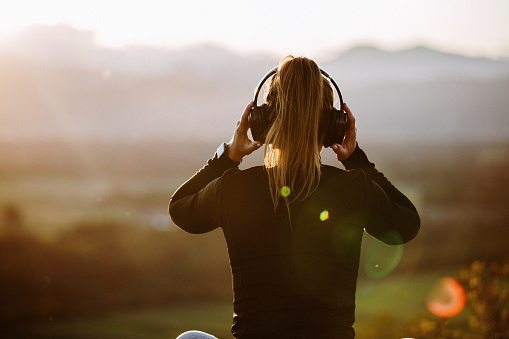 Girl with headphones listening to music at sunset