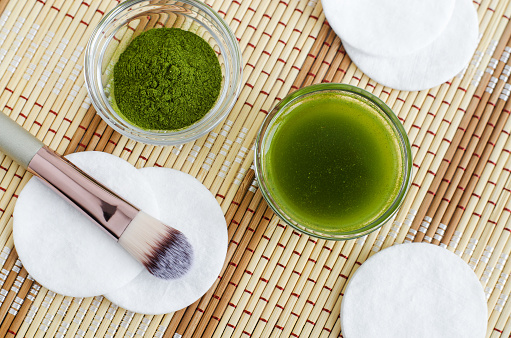 Homemade natural face toner (infusion, tincture) with matcha powder. Diy green tea cosmetics recipe. Top view, copy space
